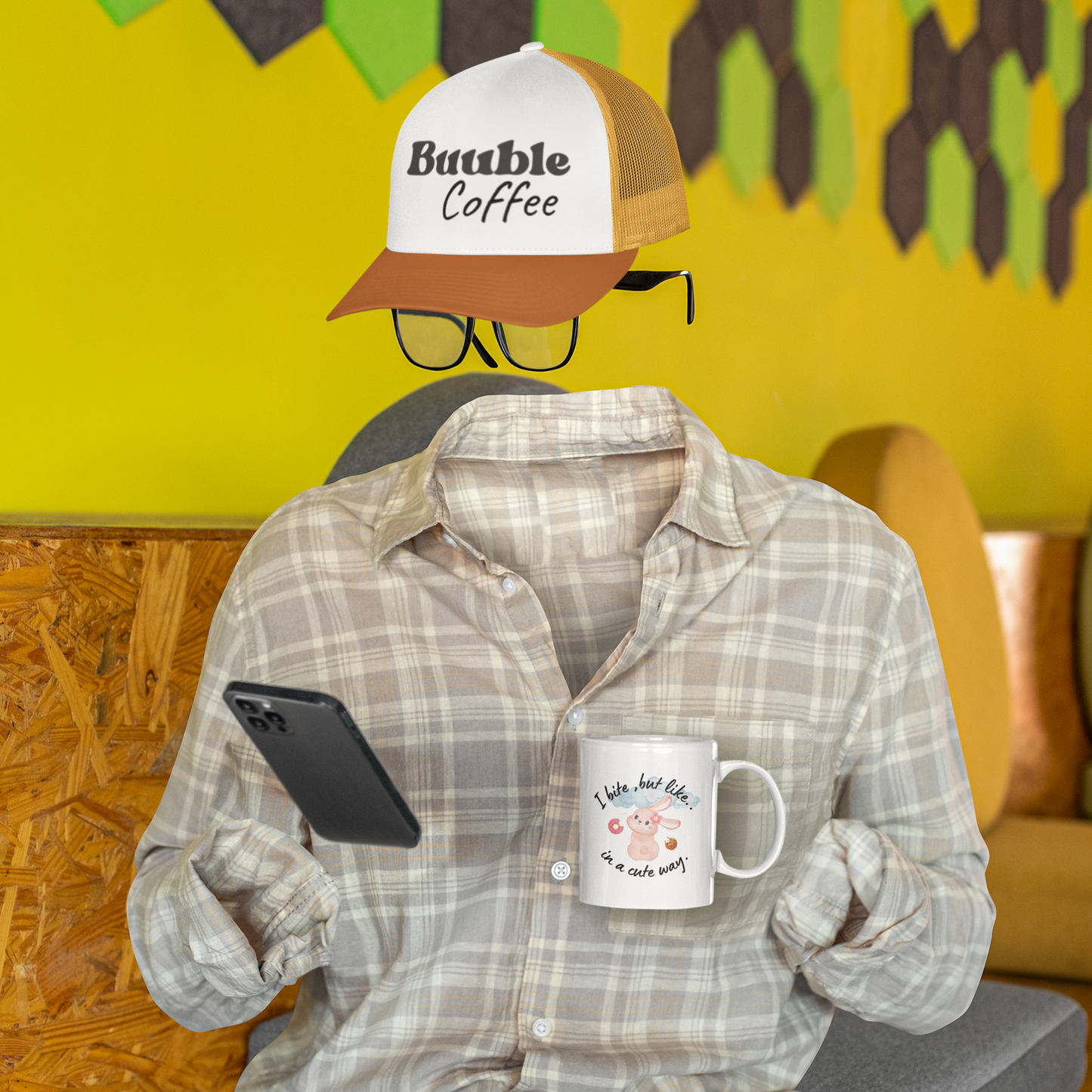 Person wearing a plaid shirt and cap holding a phone and mug against a colorful background.