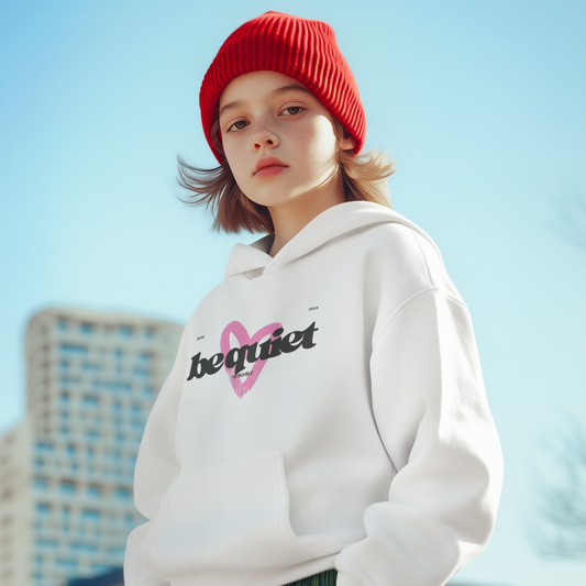 Person wearing a white hoodie with a logo and text, red beanie, and green pants against a cityscape background.