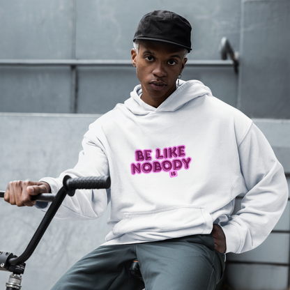 Person wearing a white hoodie with 'Be Like Nobody' text, sitting on a bike against a gray wall.