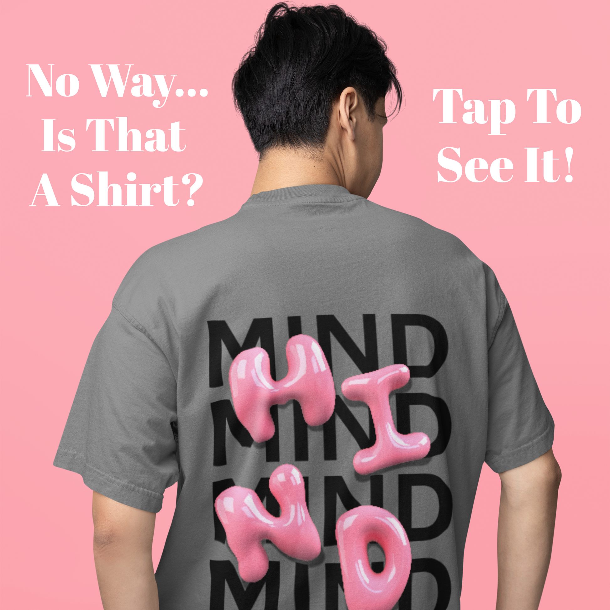 Person wearing a gray t-shirt with 'MIND' printed on the back, standing on a box against a pink background.