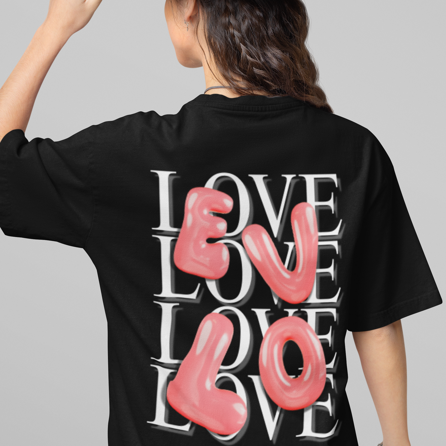 Person wearing a black t-shirt with 'LOVE' printed on the back, holding a brown hat.