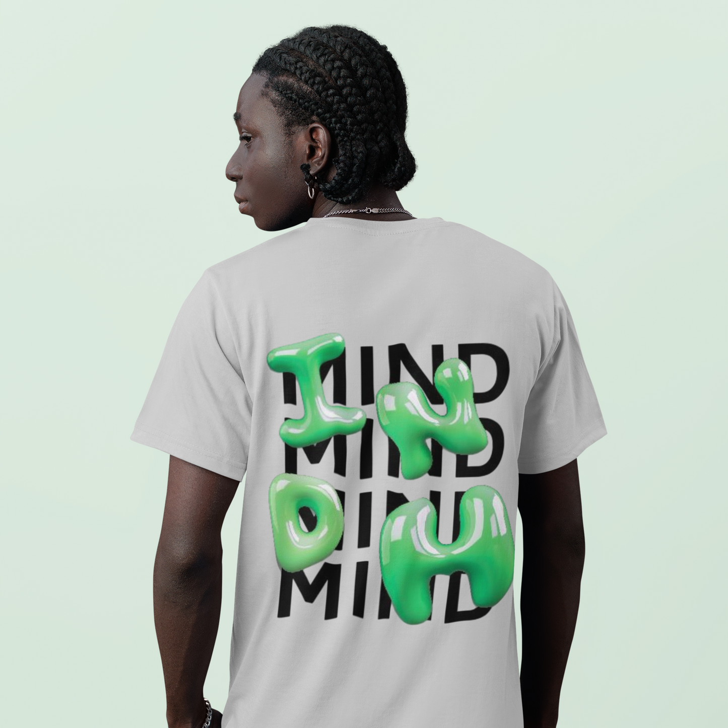 Person wearing a t-shirt with 'MIND MIND MIND' text on the back against a light green background