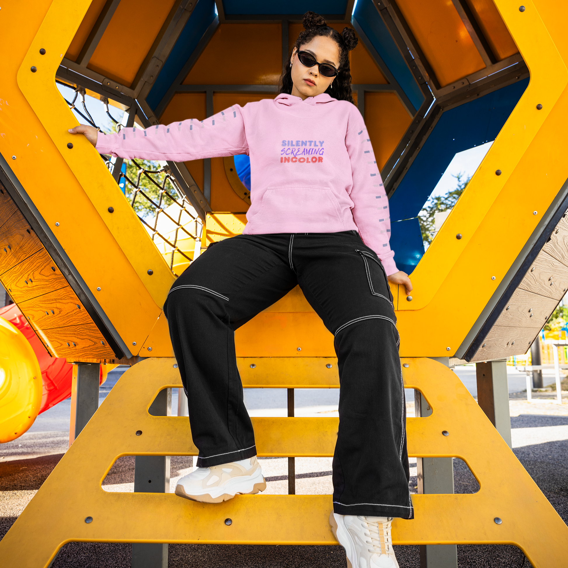 Person wearing a pink hoodie and black pants on a playground structure