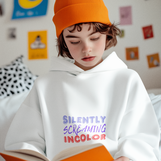 Person wearing an orange beanie and white hoodie with colorful text, reading a book in a room with posters on the wall.