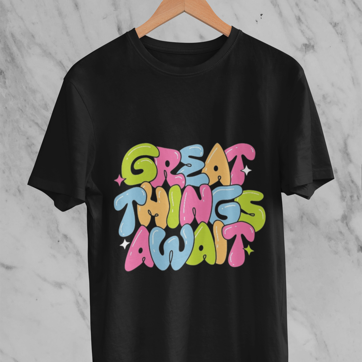 Black t-shirt with 'Great Things Await' text in colorful letters on a marble background