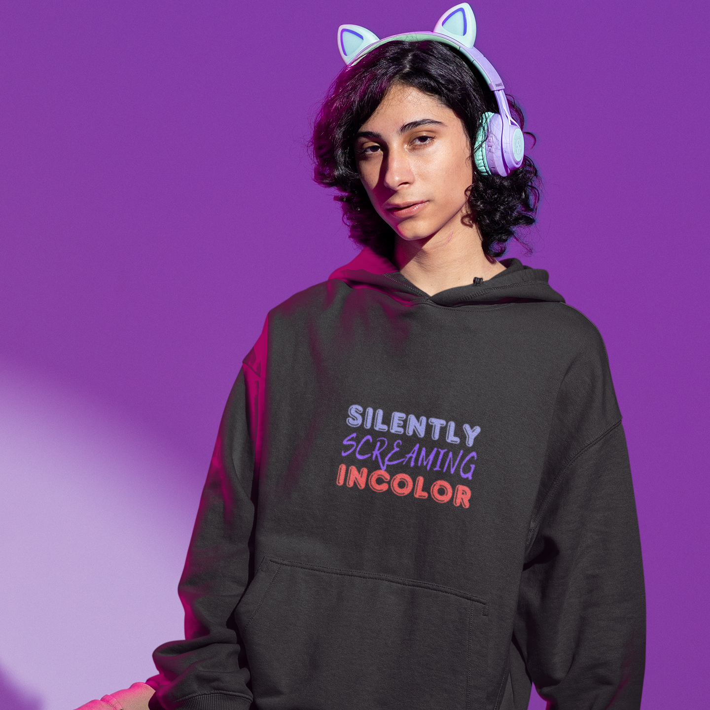 Person wearing a black hoodie with text, standing against a purple background