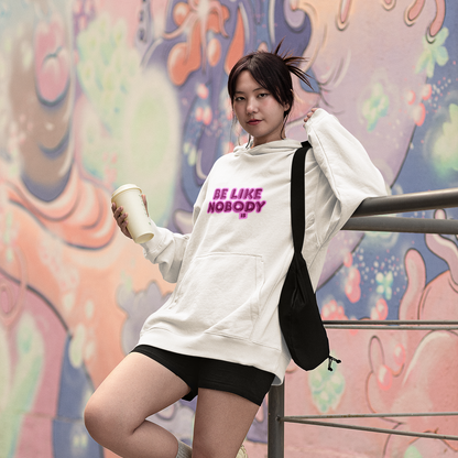 Person wearing a white sweatshirt with text, black shorts, and white sneakers against a colorful mural.