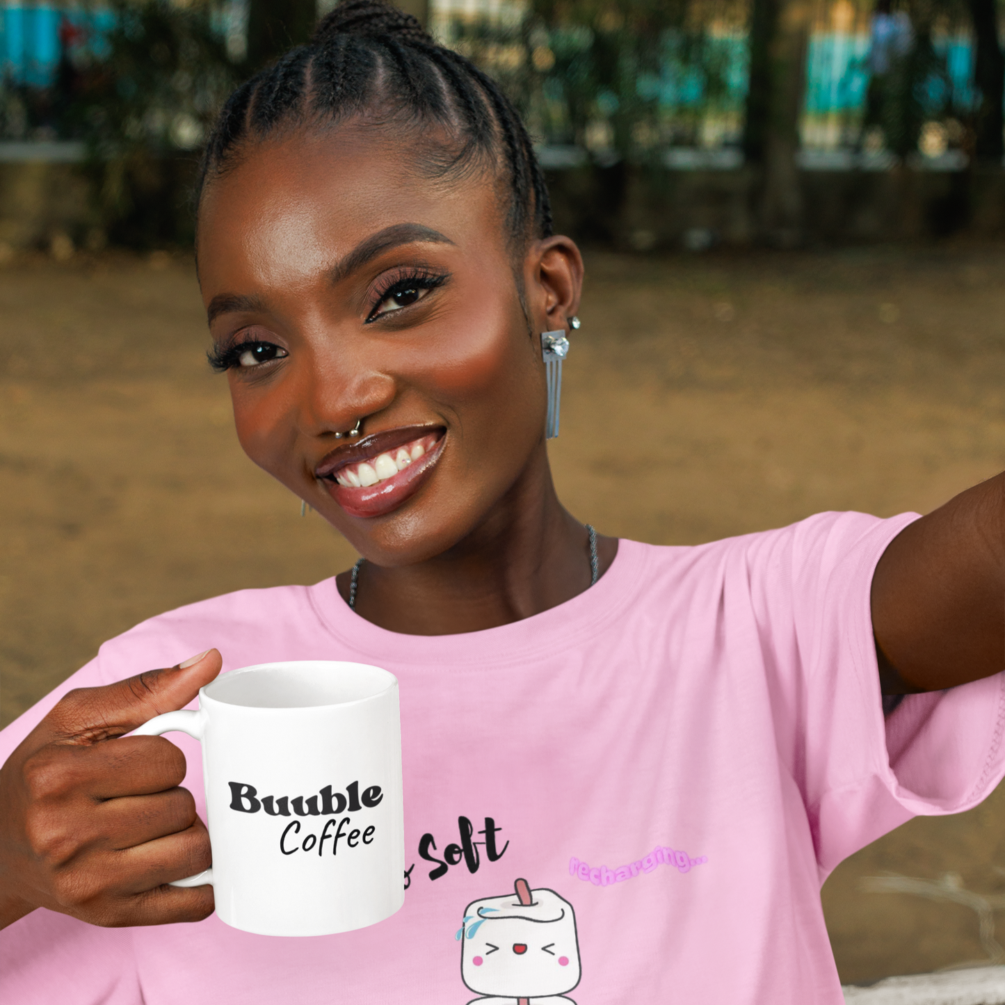 Woman holding a mug with text and graphics, wearing a pink shirt with text and graphics.