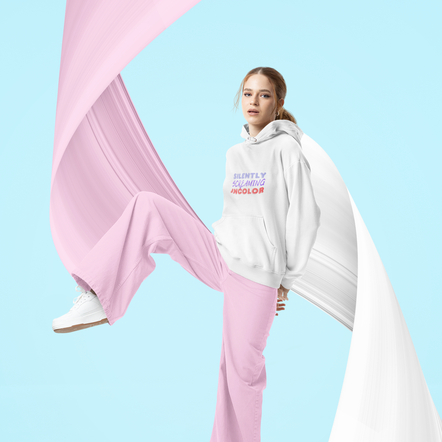 Person wearing a white hoodie with text and pink pants on a blue background