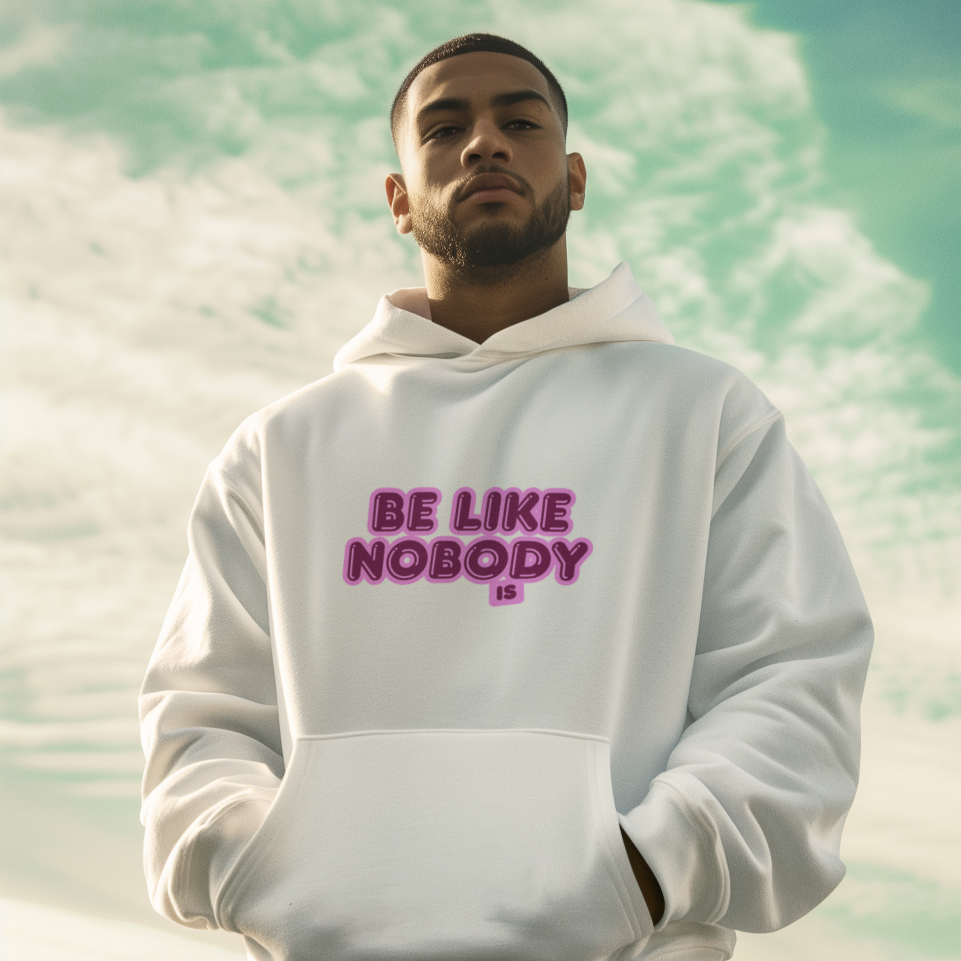 Man wearing a white hoodie with 'BE LIKE NOBODY' text against a sky and cloud background