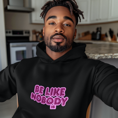 Man wearing a black hoodie with pink text in a kitchen.