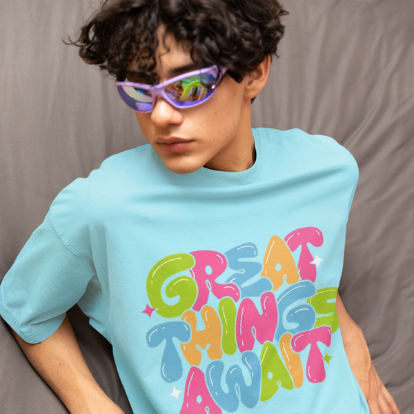 Person wearing a light blue t-shirt with colorful text and pink pants against a gray background